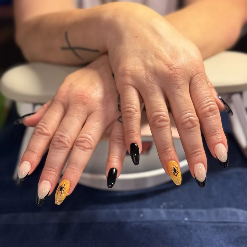 Almond nails alternating glossy black, gold and nude.