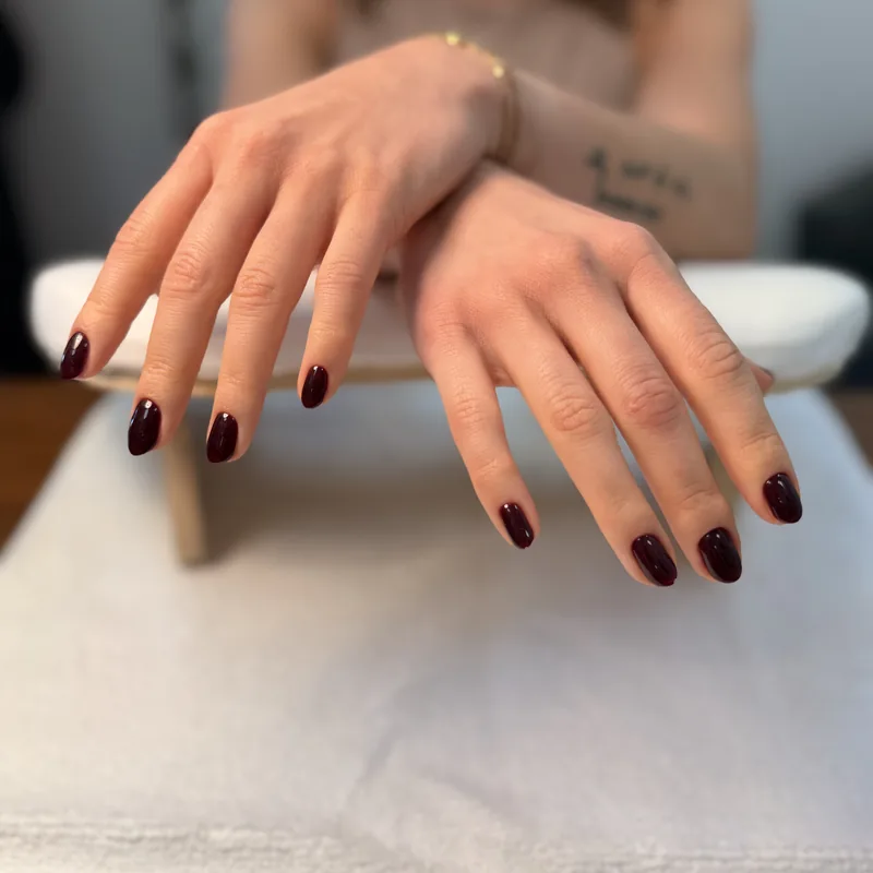 Short oval nails in a glossy deep oxblood red.