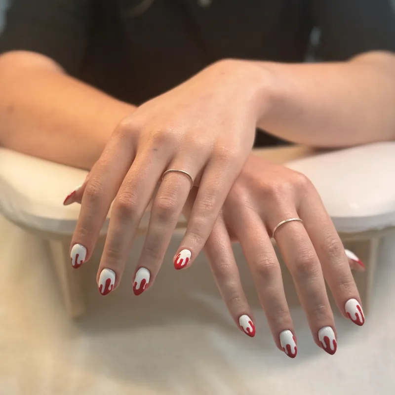 Almond nails in red and white with hand-painted striped nail art.